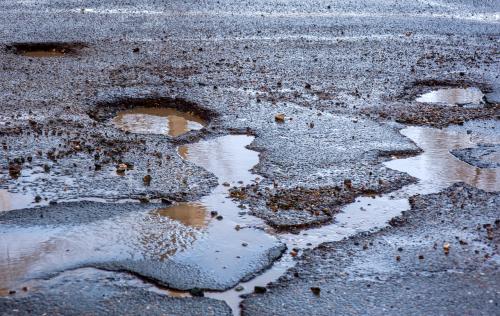 Pot holes filled with water in a damaged road.