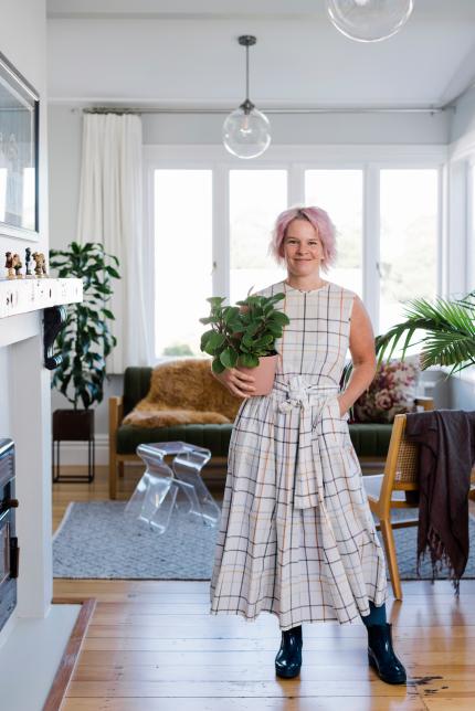 Kate Alexander from Places and Graces holds a plant in a stylish living room.