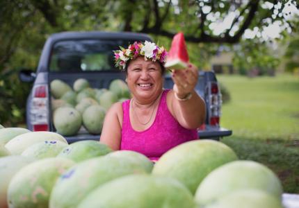 A woman offers up a fresh slice of watermelon in the Cook Islands.