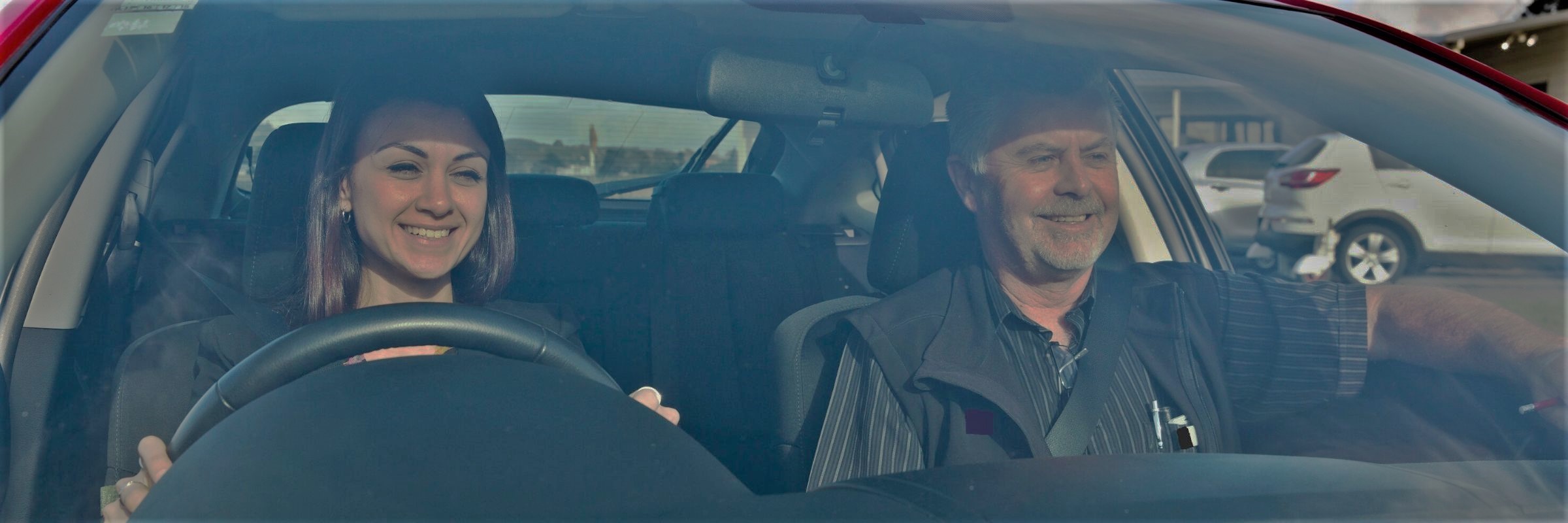 Driver and passenger smiling in car