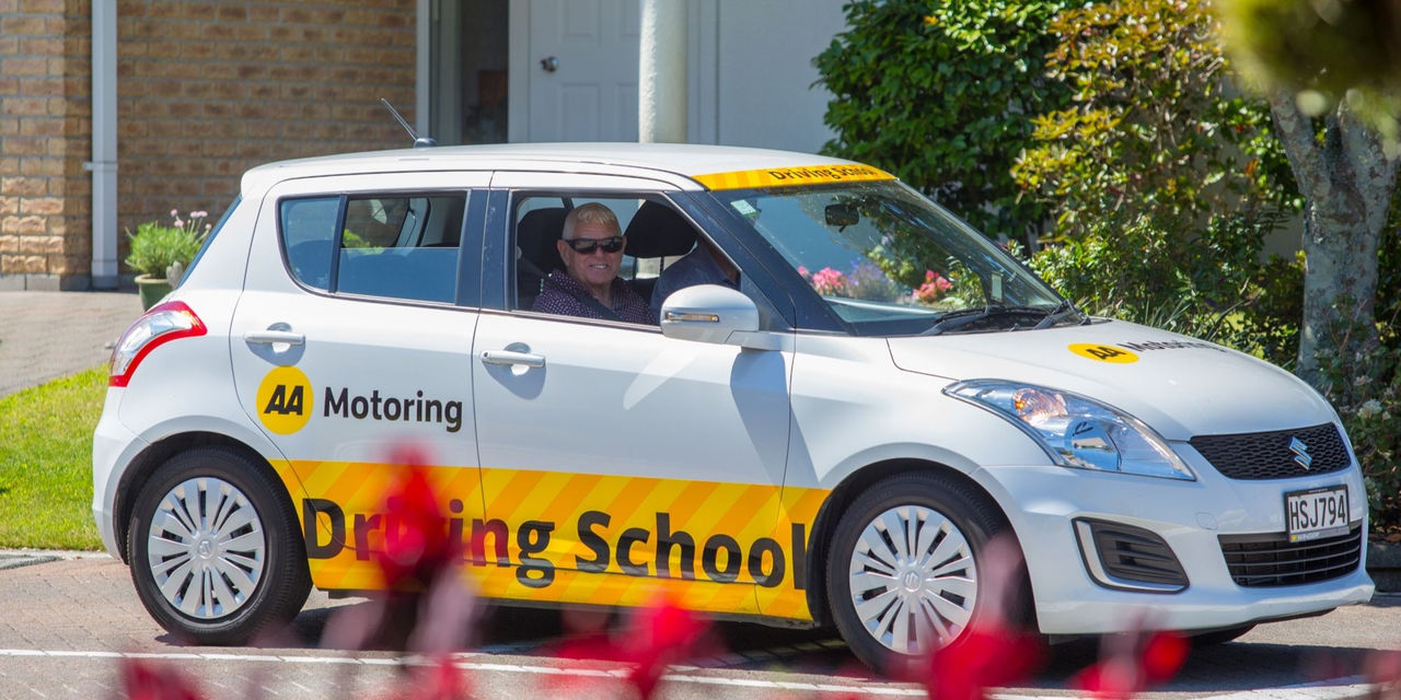 A man smiling at the camera inside an AA Motoring Driving School car